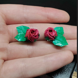 origami rose earrings held in a hand